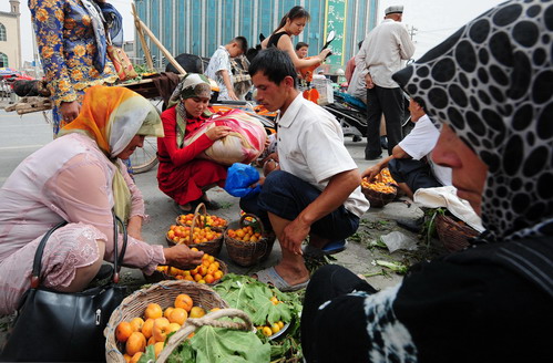 ชาวบ้านกำลังต่อรองราคาแอปพิคอตกับพ่อค้าผลไม้ในตลาดวันอาทิตย์ในเมืองคาสห์การ์ในซินเจียง เมื่อวันที่ 15 มิ.ย. ซินเจียงดินแดนของมุสลิมอุยกูร์ มีชื่อเสียงอุดมด้วยผลไม้ที่หลากหลาย เนื้อดี รสชาติอร่อย เนื่องจากน้ำจากภูเขาที่สะอาด และแสงแดดทะเลทราย