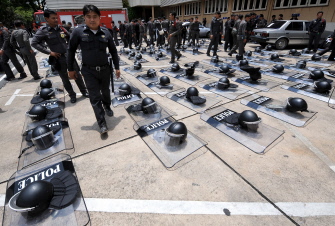 Bangkok, THAILAND : Thai riot policemen walk past their helmets and shields during an anti-government protest demonstration inside Government House in Bangkok on August 28, 2008. Thailands Prime Minister Samak Sundaravej has vowed not to use force to remove thousands of protesters camped out at the besieged government compound, and said the ball was in their court. AFP PHOTO/PORNCHAI KITTIWONGSAKUL