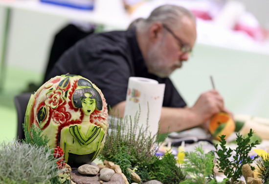 Leipzig, Saxony, GERMANY: German vegetable carver Winfried Karras sits behind his melon work of an Asian beauty on September 5, 2011 during the first European vegetable carving competition in Leipzig, eastern Germany. The competition is taking place during the Gaeste trade fair for the restaurant, hotel and catering business running until September 6, 2011. Within four hours, competitors have to carve in front of the jurys eyes a piece from melons, papayas, stem cabbage, cucumbers, radish, carrots and Chinese cabbage. AFP PHOTO/Jan Woitas 