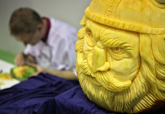 Leipzig, Saxony, GERMANY: Czech vegetable carver Radek Vach sits behind his pumpkin work of a viking on September 5, 2011 during the first European vegetable carving competition in Leipzig, eastern Germany. The competition is taking place during the Gaeste trade fair for the restaurant, hotel and catering business running until September 6, 2011. Within four hours, competitors have to carve in front of the jurys eyes a piece from melons, papayas, stem cabbage, cucumbers, radish, carrots and Chinese cabbage. AFP PHOTO/Jan Woitas 