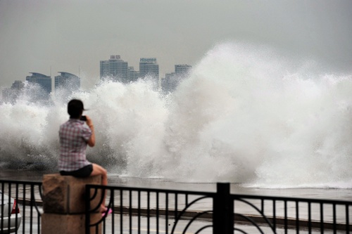 Qingdao, Shandong, CHINA: This picture taken on August 28, 2012, shows a woman watching waves brought on by Typhoon Bolaven in Qingdao, in northeast Chinas Shandong province. Typhoon Bolaven -- the strongest storm to hit South Korea for almost a decade -- left a trail of death and damage in southwestern and south-central regions of the Korean peninsula on August 28, and crossed into China early on August 29. AFP PHOTO