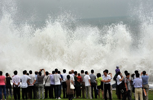 Qingdao, Shandong, CHINA: This picture taken on August 28, 2012, shows people gathered to watch waves brought on by Typhoon Bolaven in Qingdao, in northeast Chinas Shandong province. Typhoon Bolaven -- the strongest storm to hit South Korea for almost a decade -- left a trail of death and damage in southwestern and south-central regions of the Korean peninsula on August 28, and crossed into China early on August 29. AFP PHOTO