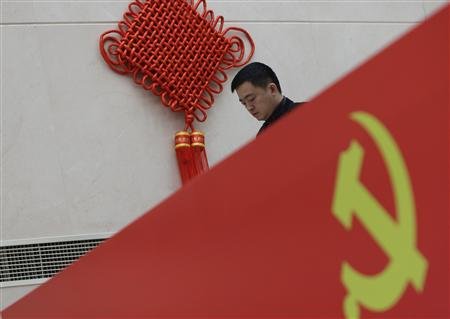 ชายจีนเดินผ่านป้ายสัญลักษณ์พรรคคอมมิวนิสต์ ในระหว่างใกล้การประชุมพรรคครั้งที่ 18 (ภาพรอยเตอร์ส)