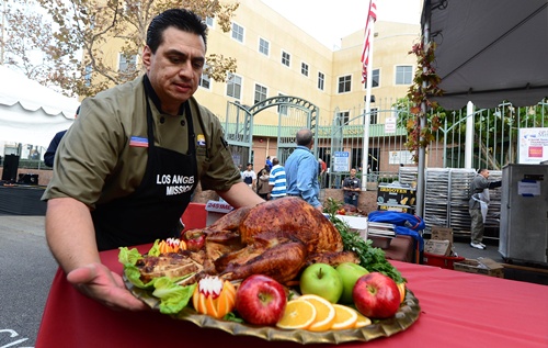 Los Angeles, California, UNITED STATES: Chef Juan Ascencio from the Los Angeles Mission brings out the first turkey for the annual Thanksgiving meal for the homeless and less fortunate in LAs skid row served by celebrities on November 21, 2012 in California. The LA Mission started as a soup kitchen for men of the depression era in 1936 and continues serving meals each day, providing emergency shelter, and helping men and women restore their lives to get back on their feet. AFP PHOTO/Frederic J. Brown