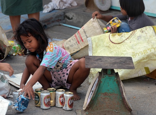 Bangkok, THAILAND: This photo taken on December 23, 2012 shows Thai children selecting used bottles and cans before trading them at a zero baht shop in Bangkok. By selling to the recycling plants in bulk, the cooperative gets a better rate than individual scavengers would manage on their own. AFP PHOTO/Pornchai Kittiwongsakul