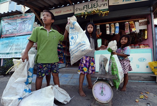 Bangkok, THAILAND: This photo taken on December 23, 2012 shows Thai children weighing packs of used bottles and cans before trading them at a zero baht shop in Bangkok. By selling to the recycling plants in bulk, the cooperative gets a better rate than individual scavengers would manage on their own. AFP PHOTO/Pornchai Kittiwongsakul