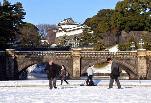 Tokyo, Tokyo, JAPAN: People walk on a snow covered field carefully at the park in front of the Imperial Palace in Tokyo on January 15, 2013 one day after heavy snowfall hit Tokyos metropolitan area. Heavy snow in eastern Japan left a man dead and at least 463 people with injures. AFP PHOTO/Yoshikazu Tsuno
