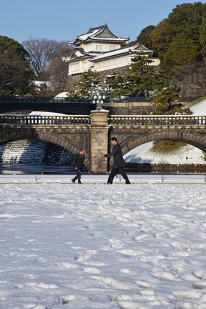 Tokyo, Tokyo, JAPAN: Businessmen carefully walk on a snow covered field at the park in front of the Imperial Palace in Tokyo on January 15, 2013 one day after heavy snowfall hit Tokyos metropolitan area. Heavy snow in eastern Japan left a man dead and at least 463 people with injures. AFP PHOTO/Yoshikazu Tsuno