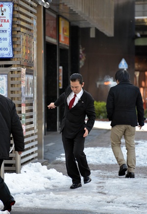 Tokyo, Tokyo, JAPAN: A businessman (C) loses his balance on a snow covered street in Tokyo on January 15, 2013 one day after heavy snowfall hit Tokyos metropolitan area. Heavy snow in eastern Japan left a man dead and at least 463 people with injures. AFP PHOTO/Yoshikazu Tsuno
