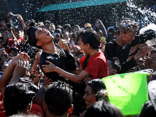 Denpasar, BALI, INDONESIA: A young Balinese couple react as they are soaked with water during a tradition called Omed-Omedan, also known as the kissing festival, in Denpasar on Bali island on March 13, 2013. The annual ritual is held one day after the Balinese Day of Silence or Nyepi. AFP PHOTO/Sonny Tumbelaka