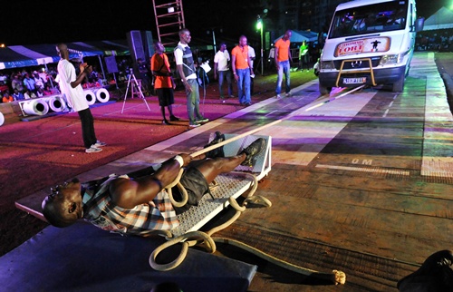 Abidjan, IVORY COAST: Okonkwo Patrick Adebayor aka Shaka Zoulou, winner of the Strongest Man of Ivory Coast strenght athletic competition, pulls a 22-seat truck weighing 5.5 tons over a distance of 12 metres during the final events of the competitions first edition in Abidjan on April 27, 2013. AFP PHOTO/Sia Kambou