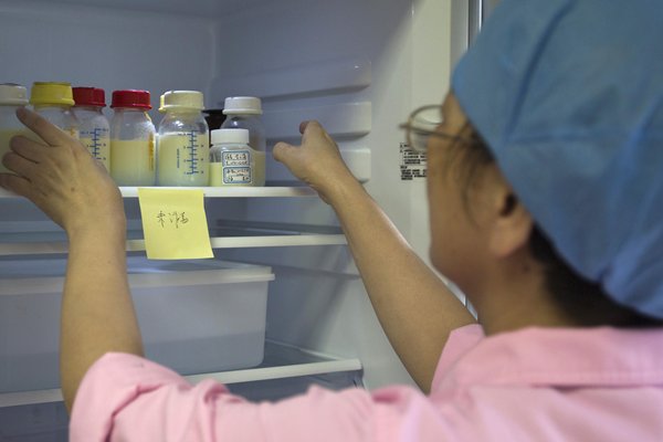 นางพยาบาลกำลังตรวจสอบนมมารดาที่ได้รับบริจาคมาในตู้เย็น (ภาพ รอยเตอร์)