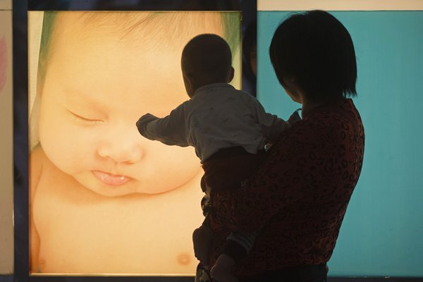 ทารกน้อยชี้โปสเตอร์ที่ติดอยู่หน้าศูนย์ผู้หญิงและเด็ก ในเมืองก่วงโจว มณฑลก่วงตง วันที่ 8 พ.ค. จีนเปิดธนาคารนมมารดาแห่งแรกของประเทศที่ศูนย์แม่และเด็กแห่งนี้ในเดือนมิ.ย.นี้ คุณแม่ราว 80 ท่านได้บริจาคนมให้แก่เด็กที่คลอดก่อนกำหนดและทารกอื่นๆที่ต้องการนมแม่ ทั้งนี้ ธนาคารนมมารดาทดลองดำเนินการมาแต่ปลายเดือนมี.ค. (ภาพ รอยเตอร์)