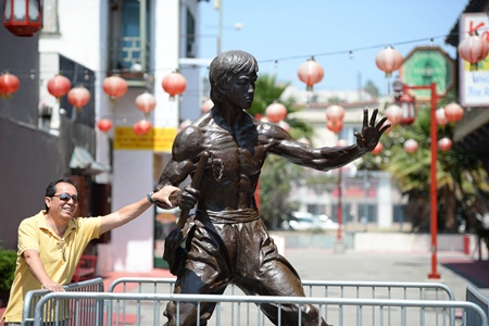 Los Angeles, California, UNITED STATES: A visitors grabs the arm of a new statue of the late martial arts icon Bruce Lee is seen in Chinatown in downtown Los Angeles June 16, 2013. The 7.6-feet (2.31 meters) tall bronze statue of the Hollywood legend was unveiled yesterday and will be on temporary display during the summer as organizers work to raise the additional US$150,000 needed to permanently install the statue. AFP PHOTO/Robyn Beck