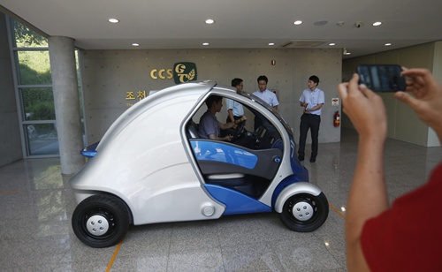 A visitor takes photographs of Armadillo-T, a foldable electric vehicle, at the Korea Advanced Institute of Science and Technology (KAIST) in Daejeon, south of Seoul September 2, 2013. With a click on a smartphone, the experimental Armadillo-T electric car made in South Korea will park itself and fold nearly in half, freeing up space in crowded cities. The quirky two-seater, named after the animal whose shell it resembles, may never see production but it is part of a trend of developing environmentally friendly vehicles for urban spaces. Picture taken September 2, 2013. REUTERS/Kim Hong-Ji 
