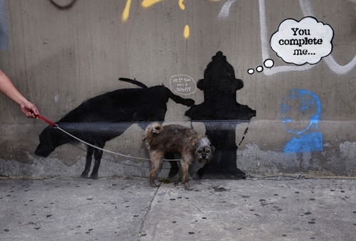 A dog urinates on a new work by British graffiti artist Banksy on West 24th street in New York City, October 3, 2013. Three new works by the street graffiti artist have appeared in New York City this week after Banksy announced a month-long residency in New York. REUTERS/Mike Segar