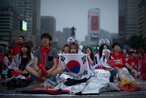 SEOUL, REPUBLIC OF KOREA: South Korean football fans react as their team loses to Algeria in the 2014 World Cup in Brazil, as they watch the match on giant screens in central Seoul on June 23, 2014. Algeria moved them tantalisingly close to a first ever appearance in the knock-out rounds after dishing out a 4-2 defeat to South Korea in Porto Alegre. AFP PHOTO/Ed Jones