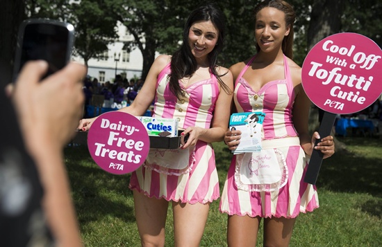 Washington, District of Columbia, UNITED STATES: Leila Sleiman (L) and Maryah Green (R) with PETA pose for photos as they hand out free Tofutti Cuties, vegan ice cream sandwiches, to raise awareness of conditions on dairy farms as well as promote a vegan lifestyle, during an event coinciding with the 32nd Annual Capitol Hill Ice Cream Party on Capitol Hill in Washington, DC, June 26, 2014. AFP PHOTO/Saul Loeb