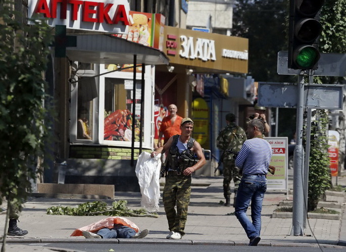 สมาชิกกลุ่มติดอาวุธนิยมรัสเซียยินข้างร่างผู้เสียชีวิตจากเหตุระดมยิงในเมืองโดเนสค์ ทางภาคตะวันออกของยูเครน เมื่อวันพฤหัสบดี (14 ส.ค.)