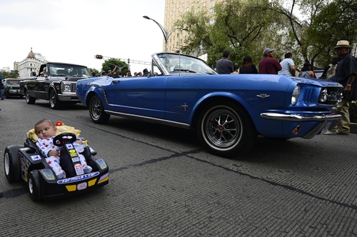 Mexico City, MEXICO: Classic cars are seen next to a baby on a car toy during an attempt to get a new Guinness record at Reforma avenue in Mexico City on October 5, 2014. The new Guinness World Record was accomplished with 1,721 classic cars. AFP PHOTO/Alfredo Estrella