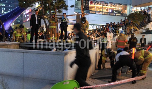 REPUBLIC OF KOREA, SEONGNAM: This picture taken on October 17, 2014 shows rescue team members checking a broken ventilation grate after concert goers fell through it into an underground parking area below in Seongnam City, south of Seoul. An official dealing with safety measures at a concert in South Korea where 16 people died when the grate they were standing on collapsed apparently committed suicide hours after the tragedy, authorities said. AFP PHOTO/Yonhap