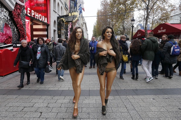 Paris, Paris, FRANCE: Two women with their bodies covered in golden paint walk during a performance for a clothes brand on the Champs Elysees avenue in Paris on December 7, 2014. AFP PHOTO/Francois Guillot