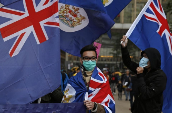 หนุ่มฮ่องกงคลุมตัวด้วยธงฮ่องกงยุคอาณานิคมและธงของสหราชอาณาจักร (เอพี)