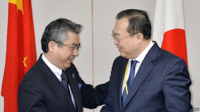 ชินสุเกะ ซูกิยามะ รัฐมนตรีช่วยว่าการกระทรวงการต่างประเทศของญี่ปุ่น (ซ้าย) และ หลิว เจียนเชา รมช.กระทรวงการต่างเทศของจีน จับมือกันก่อนการประชุมที่กรุงโตเกียวในวันที่ 19 มีนาคม ปี 2015