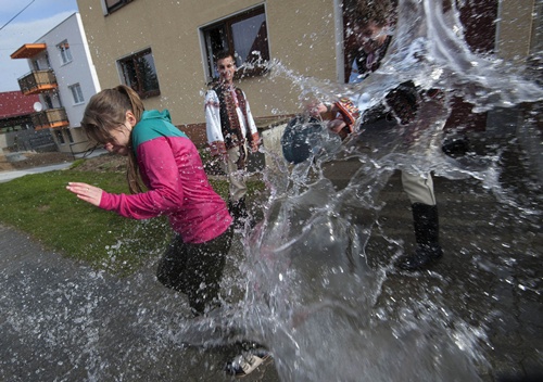 Trencianska Tepla, SLOVAKIA: A young Slovak dressed in traditional costume throws a bucket of water over a girl as part of Easter celebration in the village of Trencianska Tepla, north-western Slovakia, on April 6, 2015. AFP PHOTO/Samuel Kubani