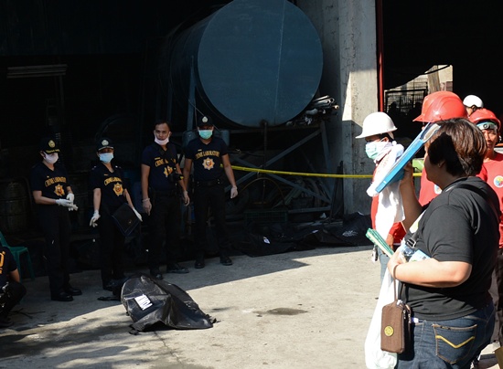 Manila, PHILIPPINES: A police forensics team stands next to a body bag containing the remains of a victim killed in a fire that gutted a footwear factory in Valenzuela city in suburban Manila on May 14, 2015, after the remains were retrieved from the burnt out building. Rescue workers carried corpses out of the charred remains of a footwear factory in the Philippine capital on Thursday as they searched for dozens of people missing following a huge fire. AFP PHOTO/Ted Aljibe