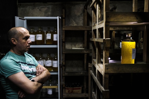 Sofia, BULGARIA: A man looks on Damask rose oil in a glass container in the vault of the state laboratory “Bulgarian Rose” on May 19, 2015 in Sofia. AFP PHOTO/Dimitar Dilkoff