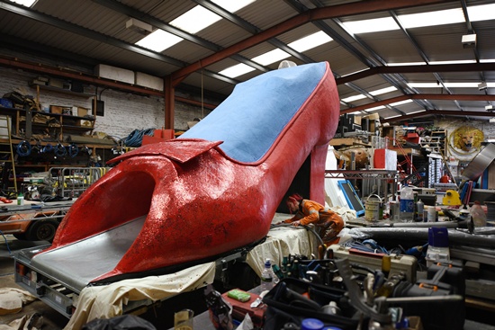 Bradford, West Yorkshire, UNITED KINGDOM: Artists for Irregular Arts put the finishing touches to a giant glitter-covered high-heeled shoe, which also features an internal slide, in Bradford, northern England, on June 9, 2015, as its is prepared for the forthcoming Bradford Festival. AFP PHOTO/Oli Scarff