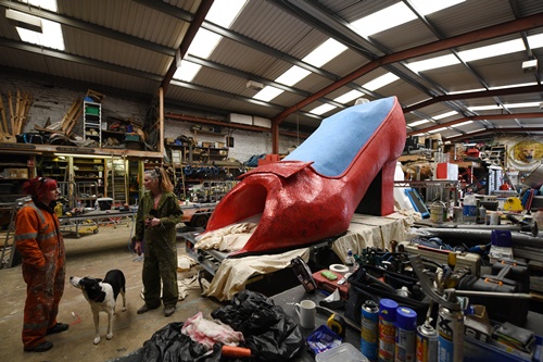 Bradford, West Yorkshire, UNITED KINGDOM: Artists for Irregular Arts put the finishing touches to a giant glitter-covered high-heeled shoe, which also features an internal slide, in Bradford, northern England, on June 9, 2015, as its is prepared for the forthcoming Bradford Festival. AFP PHOTO/Oli Scarff