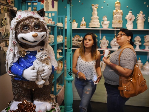 Los Angeles, California, UNITED STATES: Two women look at a USD 5500 porcelain urn called the Cat Madonna on sale to hold the ashes of deceased acts at the inaugural CatConLa event in Los Angeles, California on June 7, 2015. AFP PHOTO/Mark Ralston