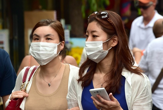 SEOUL, REPUBLIC OF KOREA: Women wearing face masks walk in a shopping district in Seoul on June 19, 2015. South Korea said on June 19 that the MERS outbreak that has killed 24 people appears to have begun subsiding, as it reported one new case -- the lowest rate of new infections in two weeks. AFP PHOTO/Jung Yeon-Je
