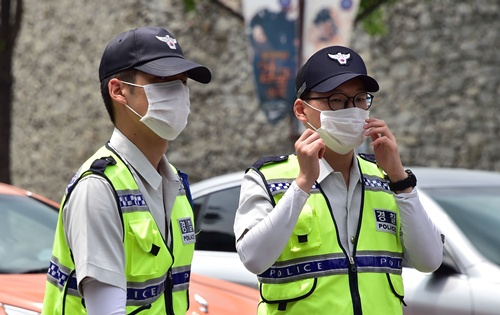 SEOUL, REPUBLIC OF KOREA: South Korean policemen wearing face masks walk on a street in downtown Seoul on June 19, 2015. South Korea said on June 19 that the MERS outbreak that has killed 24 people appears to have begun subsiding, as it reported one new case -- the lowest rate of new infections in two weeks. AFP PHOTO/Jung Yeon-Je