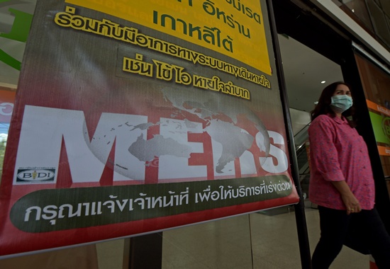 Nonthaburi, THAILAND: A Thai woman (R) walks past an information banner on Middle East Respiratory Syndrome (MERS) at the entrance of Bamrasnaradura Infectious Diseases Institute in Nonthaburi province on June 19, 2015. AFP PHOTO/Pornchai Kittiwongsakul