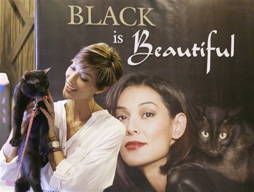 Filipino model and television personality Joey Mead holds a black cat named Sebastian as she poses next to a poster of herself during the launch of a campaign to help promote cat adoption, Monday, June 22, 2015, at suburban Pasig city east of Manila, Philippines. The Philippine Animal Welfare Society (PAWS) has unveiled a program to encourage people to adopt rescued cats to stop its overpopulation. (AP Photo/Bullit Marquez)