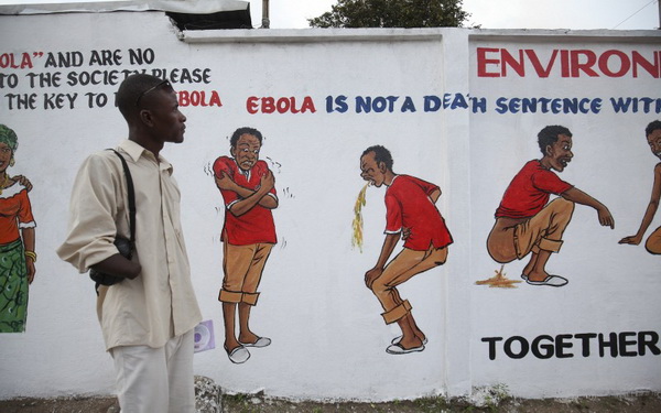 ชาวบ้านในเซียร์ราลีโอนอ่านป้ายคำแนะนำเกี่ยวกับอีโบลา ขณะที่ไวรัสมรณะชนิดนี้กลับมาแพร่ระบาดอีกครั้งในเมืองหลวง