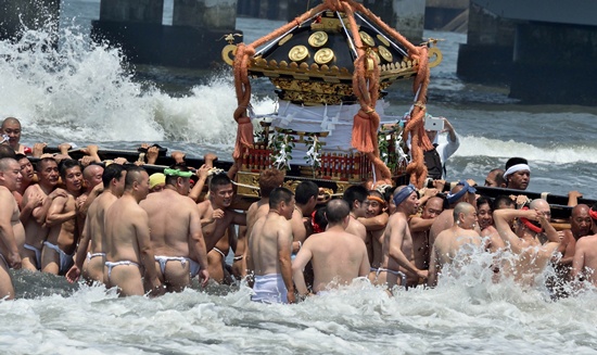 FUJISAWA, JAPAN: Believers carry a portable Shinto shrine into the sea to purify themselves during the annual Enoshima Tenno festival in Fujisawa, suburban Tokyo on July 12, 2015. AFP PHOTO/Kazuhiro Nogi