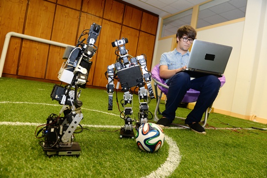 Bordeaux, Gironde, FRANCE: Robots play football next to a scientist at the LABRI Laboratory (computer science research center) in Bordeaux on July 3, 2015. AFP PHOTO/Jean Pierre Muller