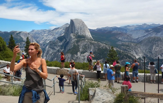 Yosemite National Park, California, UNITED STATES: This August 5, 2015 photo shows a woman taking a selfie atop Glacier Point with a background view of Half Dome at Yosemite National Park. A second tourist who visited Yosemite National Park has likely contracted the plague, Californian authorities said. The unnamed individual, from the southern US state of Georgia, had vacationed in Yosemite, the Sierra National Forest and surrounding areas in California early this month. Warnings issued in California regarding plague were useful all the way across the country in Georgia, Karen Smith, the director and state health officer for the California Department of Public Health said on August 18, 2015. AFP PHOTO/Frederic J. Brown