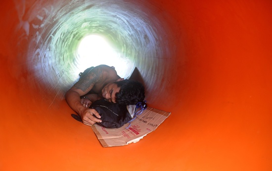 Manila, PHILIPPINES: A Filipino man sleeps inside a plastic water pipe in the compound of a water company in Manila on September 9, 2015. AFP PHOTO/Jay Directo