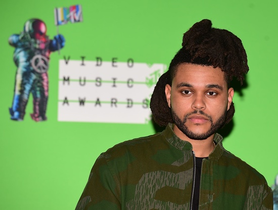 Los Angeles, California, UNITED STATES: (FILES) In this August 30, 2015 file photo, Canadian recording artist The Weeknd poses for a photo in the press room at the MTV Video Music Awards (VMA), at the Microsoft Theater in Los Angeles, California. Canadian singer The Weeknd on September 16, 2015 proved himself to be a fast-rising star as he pulled off the rare feat of topping three premier US charts. The Weeknd has scored a major summer hit with Cant Feel My Face, whose wide-ranged pop vocals over a funky bassline have drawn comparisons to Michael Jackson. The song rose to number one on the Billboard singles chart, replacing the latest by Justin Bieber, with another song by The Weekend, The Hills, at number two. The Weeknds album, Beauty Behind the Madness, meanwhile spent a second week at number one. he also topped for the sixth week Billboards Artist 100, which tracks all activity including radio airplay and social media sharing. AFP PHOTO/Frederic J. Brown/Files