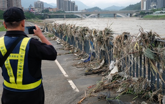 NEW TAIPEI CITY, TAIWAN: A security guard takes a photo of debris at the Xindian river banks in the New Taipei City on September 29, 2015. Super typhoon Dujuan killed two and left more than 300 injured in Taiwan before making landfall in China. AFP PHOTO/Sam Yeh