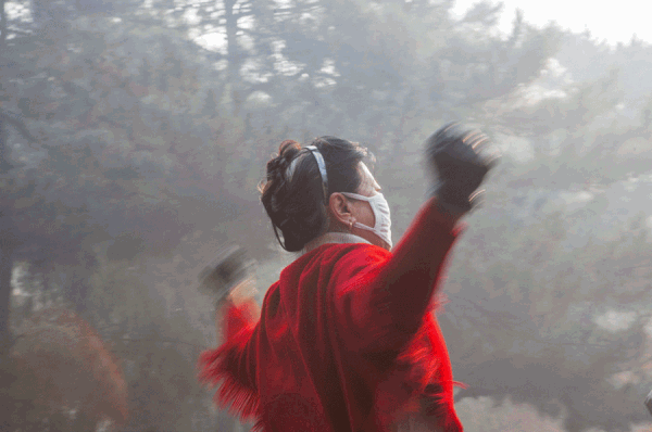 หญิงชาวจีนสวมหน้ากากอนามัยป้องกันหมอกพิษขณะออกกำลังกายยามเช้า วันที่ 26 ต.ค. 2558 (ภาพ ซินหวา)