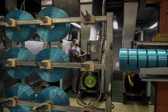 Angles, SPAIN: An employee works behind spools of yarn made using plastic waste at a yarn proccessing plant in Angles, north-eastern Spain on November 6, 2015. AFP PHOTO/Pedro Armstre