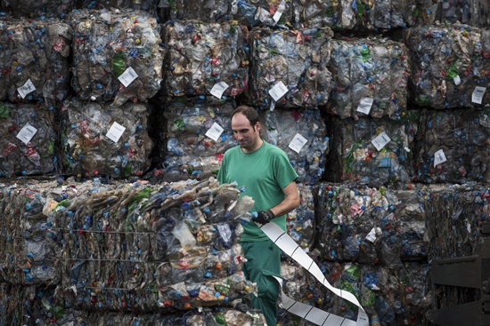 Chiva, SPAIN: An employee works near stacks of plastic waste collected in the sea by fishermen at a plastic processing plant in Chiva, near Valencia on November 3, 2015. Ecoalf, a Spanish Madrid-based firm founded in 2010, has already launched a new generation of clothes and accessories made from plastic bottles, old fishing nets and used tires found on land. AFP PHOTO/Pedro Armstre