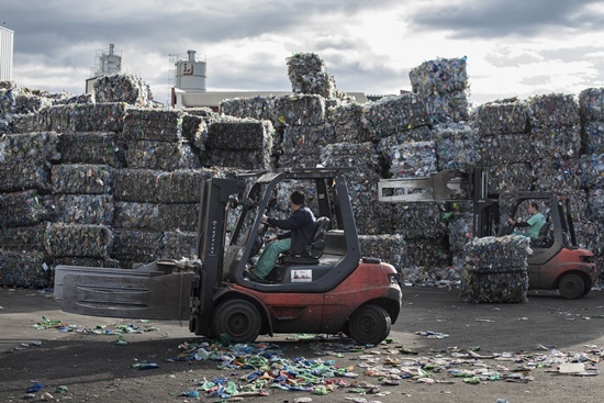 Chiva, SPAIN: An employee drives a forklift past stacks of plastic waste collected in the sea by fishermen at a plastic processing plant in Chiva, near Valencia on November 3, 2015. AFP PHOTO/Pedro Armstre