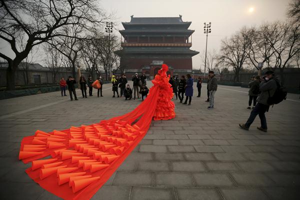 ศิลปินหญิงชาวจีน ข่ง หนิง โชว์การแสดงศิลปะในย่านประวัติศาสตร์นครปักกิ่ง เพื่อกระตุ้นจิตสำนึกต่ออันตรายจากหมอกควันเมื่อวันที่ 7 ธ.ค. (ภาพ รอยเตอร์ส)